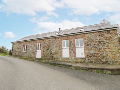A stone building with windows and a door at Y Felin in Cardigan, Ceredigion