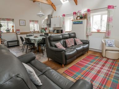 A living room with a sofa and dining area at Y Felin in Cardigan, Ceredigion