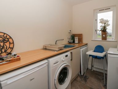 A laundry room with a washing machine and a counter at Y Felin in Cardigan, Ceredigion