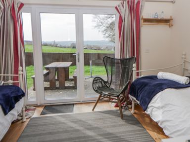 A bedroom with a chair and two beds at Y Felin in Cardigan, Ceredigion