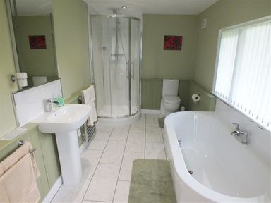 A bathroom with a bathtub shower toilet and sink at Pond Cottage in New Quay Ceredigion