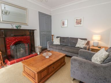 A living room with a fireplace and sofa at Dewi Villa in Aberarth, Ceredigion