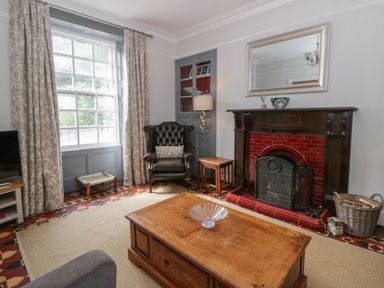 A living room with a fireplace and armchair at Dewi Villa in Aberarth, Ceredigion