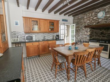 A kitchen with wooden cabinets and a dining table at Dewi Villa in Aberarth, Ceredigion