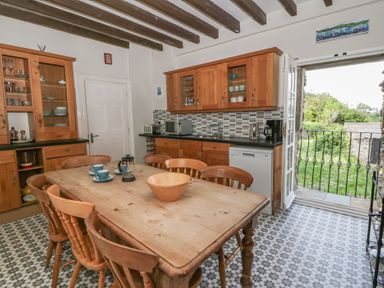 A kitchen with a wooden table and chairs at Dewi Villa in Aberarth, Ceredigion