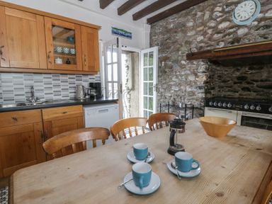 A kitchen with wooden cabinets and a dining table at Dewi Villa in Aberarth, Ceredigion