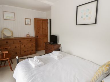 A bedroom with a bed, dresser, and television at Dewi Villa in Aberarth, Ceredigion