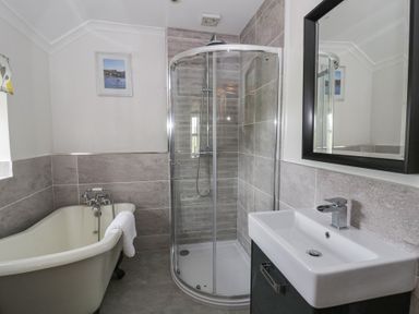 A bathroom with a bathtub, shower, and sink at Dewi Villa, Aberarth, Ceredigion