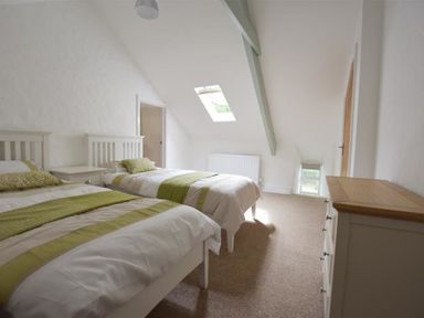 A bedroom with two single beds and a chest of drawers at The Old Farmhouse Kitchen in St Davids Pembrokeshire