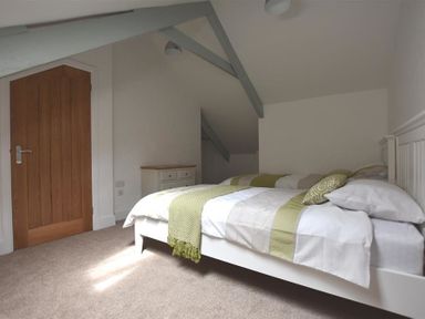 A bedroom with a bed a wooden door and a dresser at The Old Farmhouse Kitchen in St Davids Pembrokeshire
