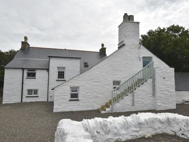 Exterior view of a white stone house with a staircase leading to an upper door at The Old Farmhouse Kitchen in St Davids Pembrokeshire