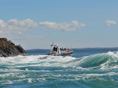 A boat on choppy water near rocky coast with people on board at The Old Farmhouse Kitchen in St Davids Pembrokeshire