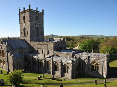 A large stone church with a square tower and arched windows surrounded by green lawns and gravestones at The Old Farmhouse Kitchen in St Davids Pembrokeshire