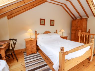 A bedroom with a bed and wooden furniture at Dan Castell Cottage in Llandeilo, Carmarthenshire