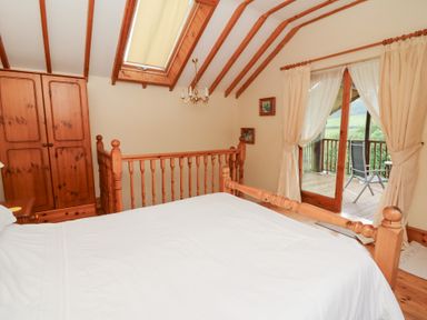 A bedroom with a bed and wardrobe at Dan Castell Cottage in Llandeilo, Carmarthenshire
