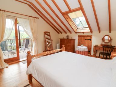 A bedroom with a bed and wooden furniture at Dan Castell Cottage in Llandeilo, Carmarthenshire