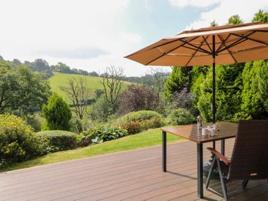 A garden with a table and chairs under an umbrella at Dan Castell Cottage in Llandeilo, Carmarthenshire