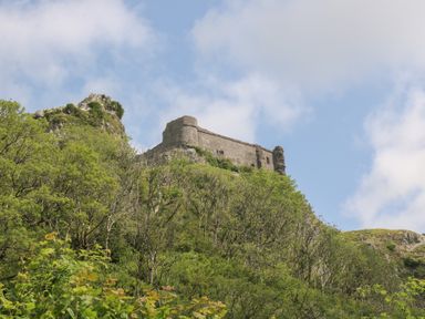 A castle on a hill with trees in the foreground at Dan Castell Cottage, Llandeilo, Carmarthenshire