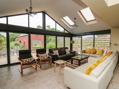 A living room with sofas chairs and glass walls at Nevern House in Newport Pembrokeshire