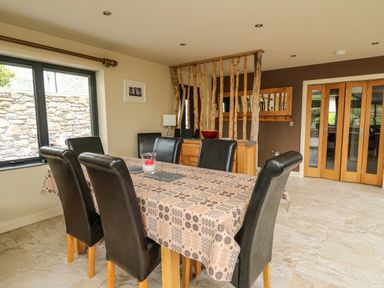 A dining room with a table covered by a patterned tablecloth and six black chairs at Nevern House in Newport Pembrokeshire