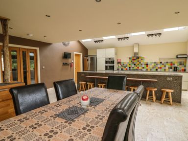 A kitchen and dining area with a table covered by a patterned cloth and black chairs at Nevern House in Newport Pembrokeshire
