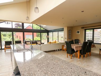 An open living and dining area with a granite kitchen island and leather dining chairs at Nevern House in Newport Pembrokeshire