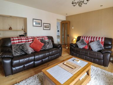 A living room with two leather sofas cushions and a wooden coffee table at Nevern House in Newport Pembrokeshire