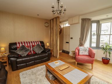 A living room with a leather sofa pillows a red armchair and a wooden coffee table at Nevern House in Newport Pembrokeshire