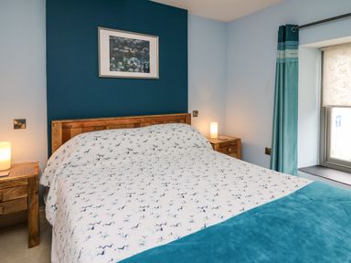A bedroom with a wooden bed and bedside tables with lamps at Nevern House in Newport Pembrokeshire