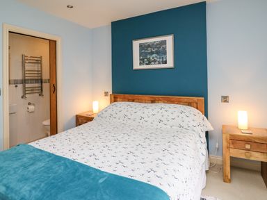 A bedroom with a double bed bedside tables lamps and an open door to a bathroom at Nevern House in Newport Pembrokeshire