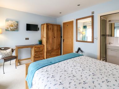 A bedroom with a bed a wooden wardrobe a desk a chair and an attached bathroom at Nevern House in Newport Pembrokeshire