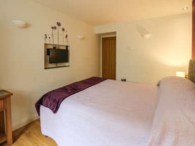 A bedroom with a bed covered with a light bedspread and a purple blanket at Nevern House in Newport Pembrokeshire