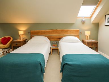A bedroom with two single beds with white bedding and teal blankets at Nevern House in Newport Pembrokeshire