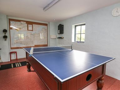 A room with a ping pong table a window a wall clock maps on the wall and a red stool at Nevern House Newport Pembrokeshire