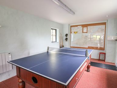 A game room with a ping pong table cue sticks on a stand maps on the wall and a red stool at Nevern House in Newport Pembrokeshire