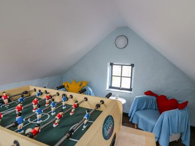 A game room with a foosball table and two chairs covered with blue blankets at Nevern House in Newport Pembrokeshire