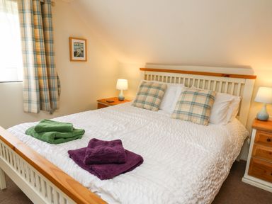 A bedroom with a wooden bed and two bedside tables with lamps at Panteg Cottage Newport Pembrokeshire