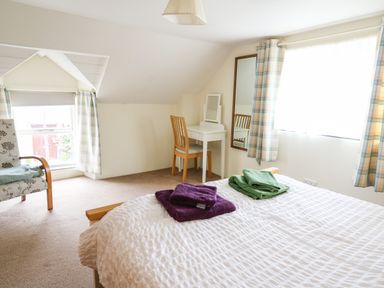 A bedroom with a bed with folded towels a chair a small desk with a chair and a mirror at Panteg Cottage Newport