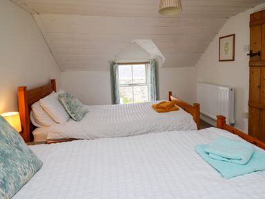 A bedroom with two single beds white bedding and folded towels on each bed at Panteg Cottage Newport Pembrokeshire