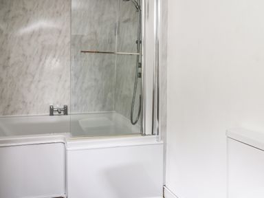 A bathroom with a bathtub and shower enclosure at Panteg Cottage Newport