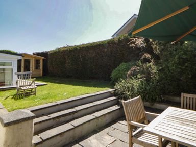A garden with wooden chairs, table, and steps at Dolwylan in Newport, Pembrokeshire