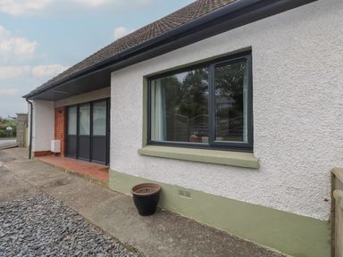 The exterior of a house with a window and sliding door a black flower pot on the ground at Greenfields in St Davids Pembrokeshire