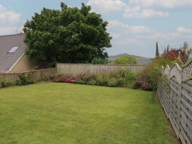 A garden with grass lawn wooden fences and flowering plants at Greenfields in St Davids Pembrokeshire