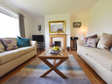 A living room with two beige sofas a wooden coffee table and a fireplace at Greenfields in St Davids Pembrokeshire