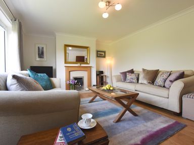 A living room with two beige sofas a wooden coffee table with fruit and a fireplace at Greenfields in St Davids Pembrokeshire