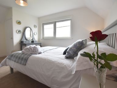 A bedroom with a bed with pillows and folded towels a dressing table with a mirror and plates on the wall at Greenfields in St Davids Pembrokeshire