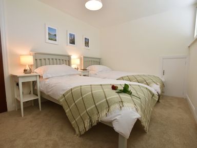 A bedroom with two single beds with checked blankets and a red rose on one bed at Greenfields in St Davids Pembrokeshire