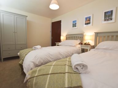A bedroom with two single beds side by side with white linens and green blankets at Greenfields in St Davids Pembrokeshire