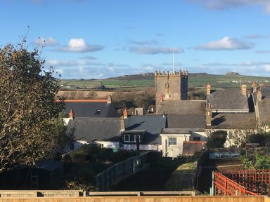 A village with houses and a church tower with hills in the background at Greenfields in St Davids Pembrokeshire