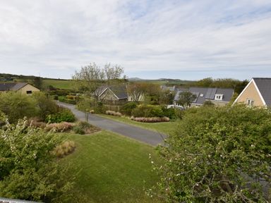 A view of houses with gardens and trees along a road with hills in the background at Greenfields in St Davids Pembrokeshire